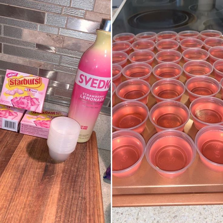 there are many cups on the counter and one is filled with pink liquid next to an empty cup