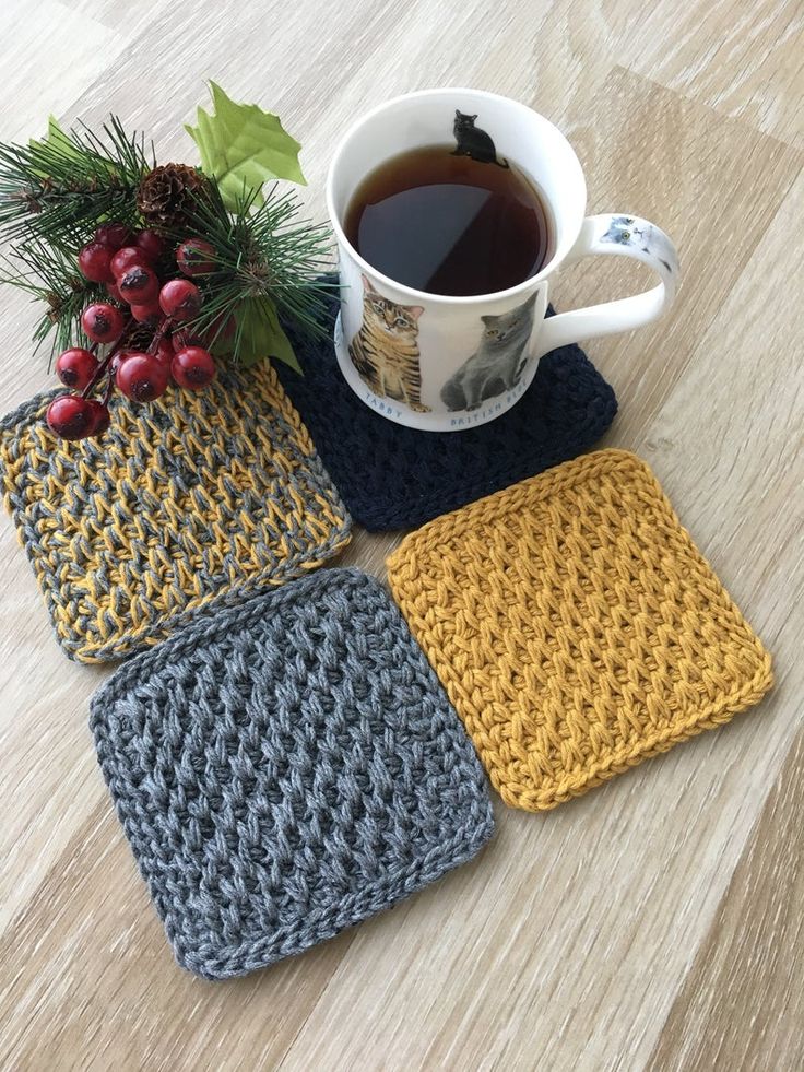 four crocheted coasters with a cup of coffee and berries on the table