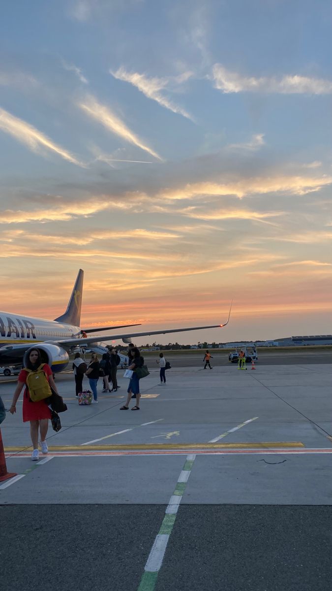 several people are walking towards an airplane on the tarmac at sunset or sunrise time