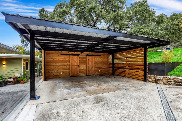 an empty garage with two doors open in front of a green yard and trees on the other side