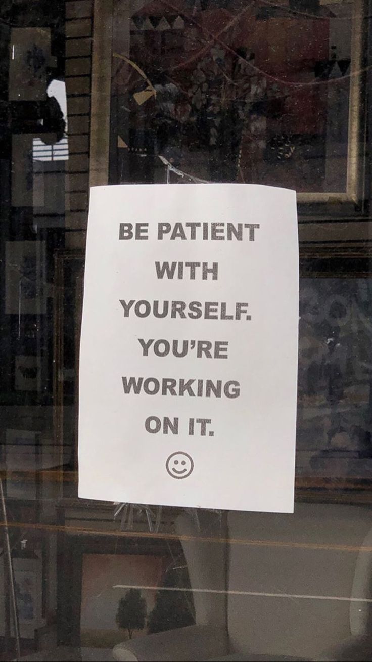 a sign that is on the window of a store saying be patient with yourself, you're working on it