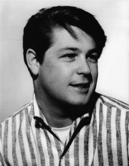 a black and white photo of a man wearing a striped shirt