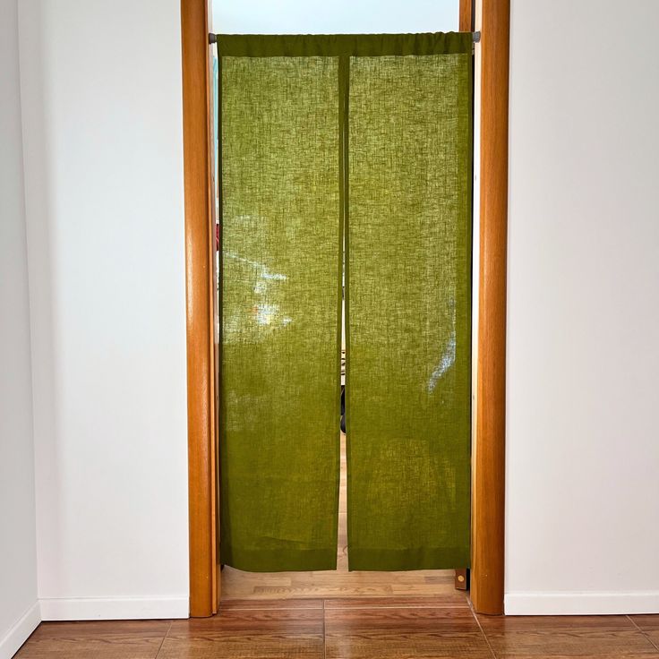 an open door with green fabric covering the doors and wood trimmings on it