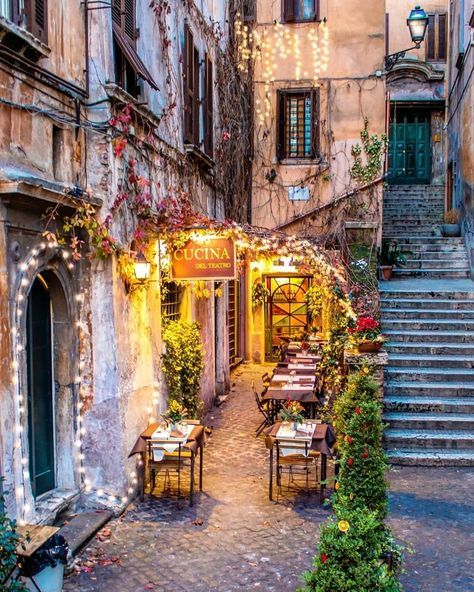 an alleyway with tables and chairs in front of some old buildings at night time