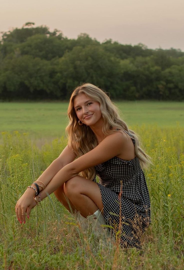 a beautiful young blond woman kneeling in a field