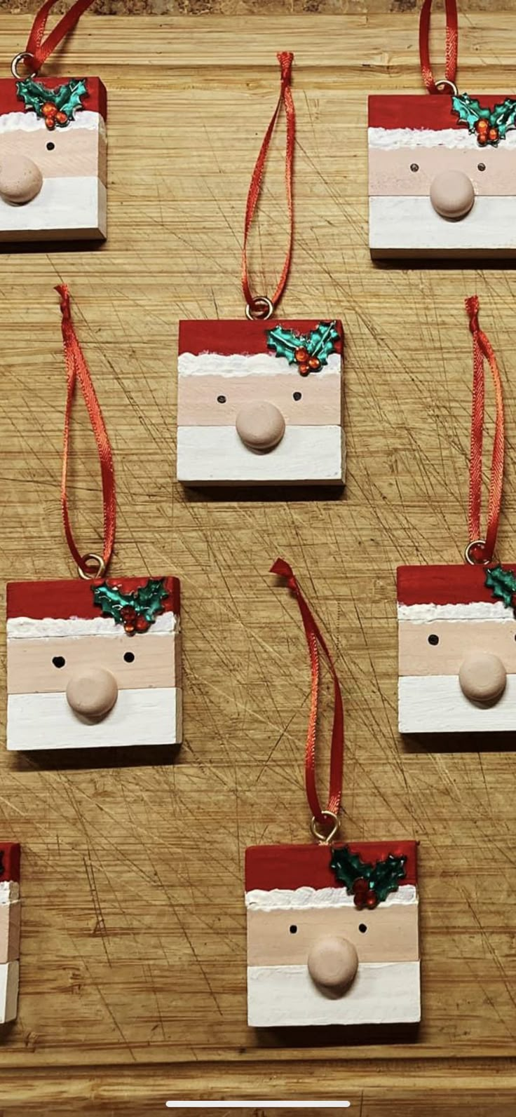 wooden ornaments with santa's head on them are hanging from red and white ribbons