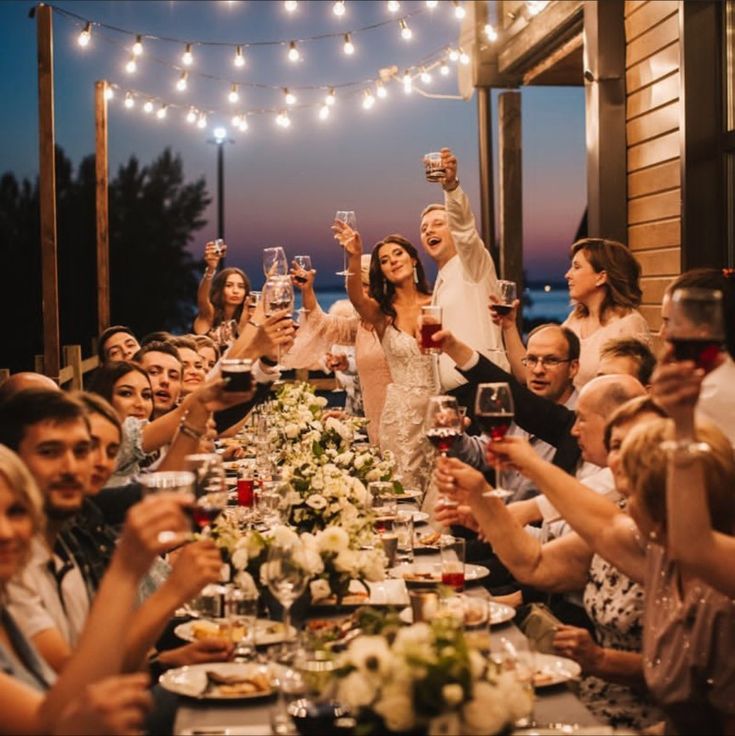 a group of people sitting around a long table with food and drinks in front of them