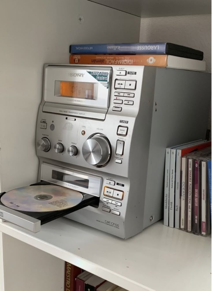 an old radio sitting on top of a book shelf next to a cd player and books