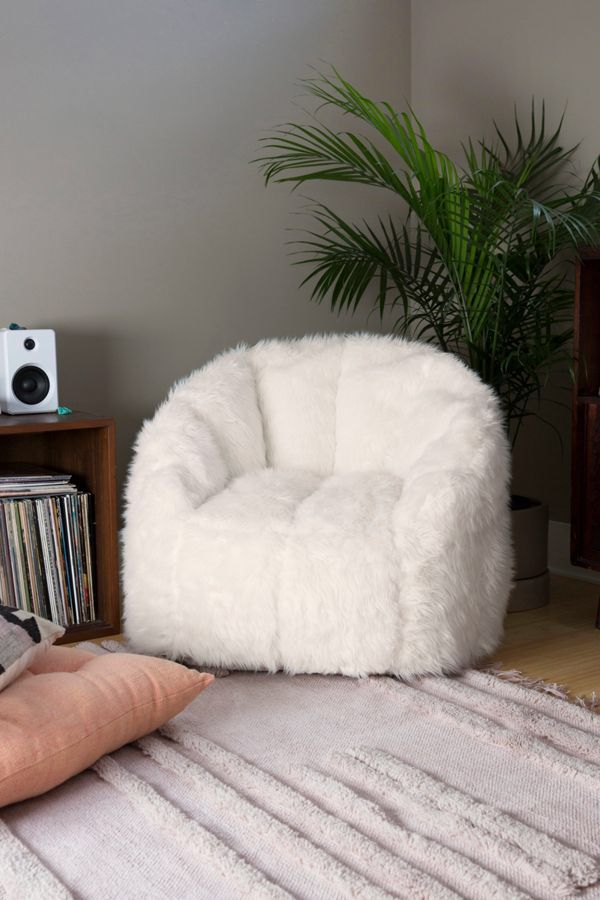 a white chair sitting on top of a rug next to a plant