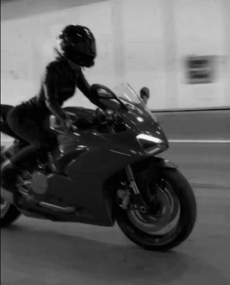 a man riding on the back of a motorcycle in a parking garage next to a building