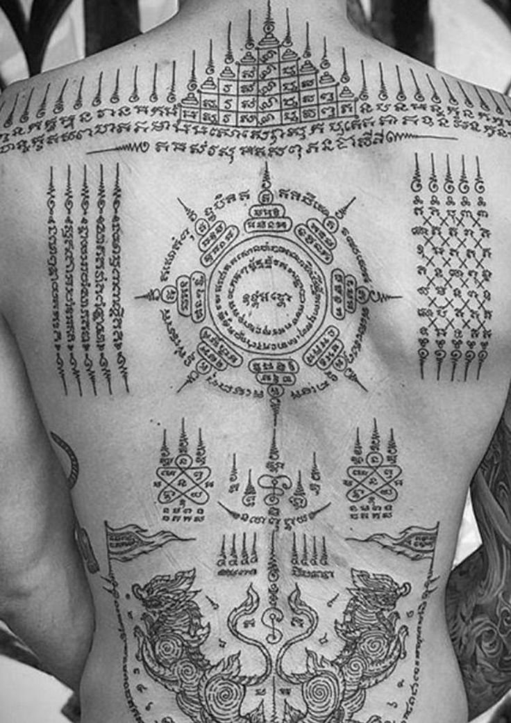 the back of a man with tattoos on his body and various symbols around him, all in black and white