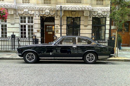 an old black car parked in front of a building