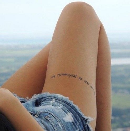 a woman's legs with writing on the back of her leg, in front of a cityscape