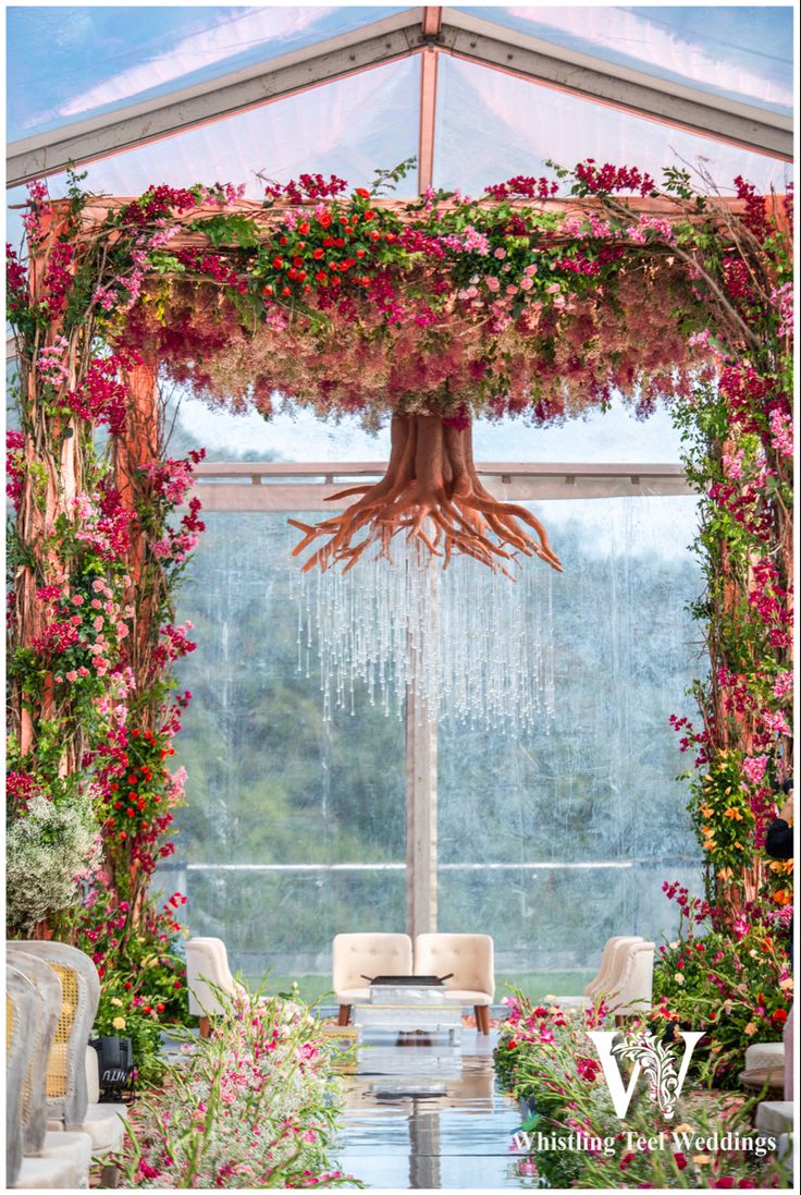 an outdoor wedding venue with flowers and greenery on the ceiling, decorated with hanging chandelier