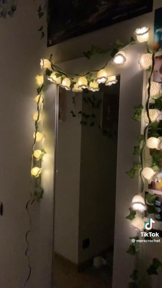 a mirror with some lights on it in a room that is decorated with vines and flowers