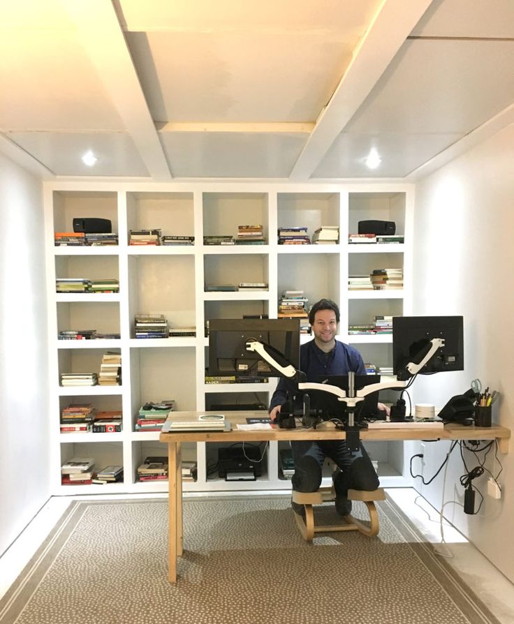 a man sitting at a desk in front of a book shelf with books on it