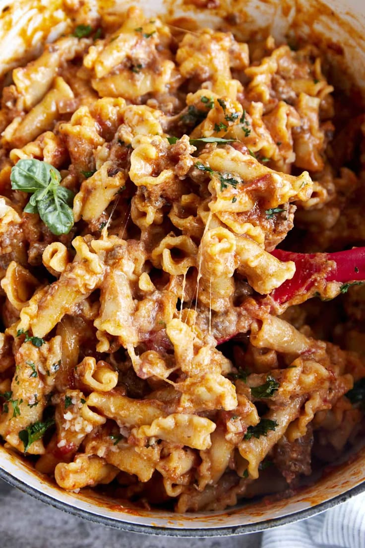 a pot full of pasta with meat and parsley on the side, ready to be eaten