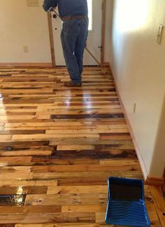 a man standing on top of a hard wood floor next to a blue drainer