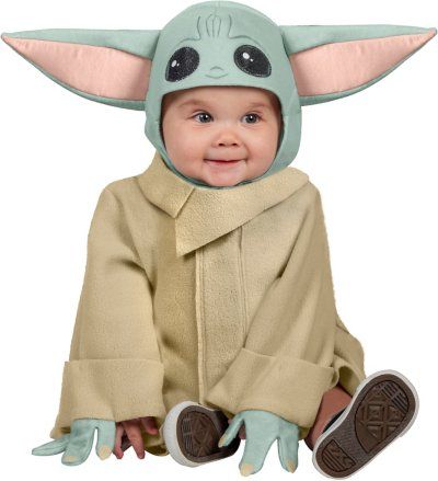 a baby yoda costume sitting on the ground with its hands in the air and smiling