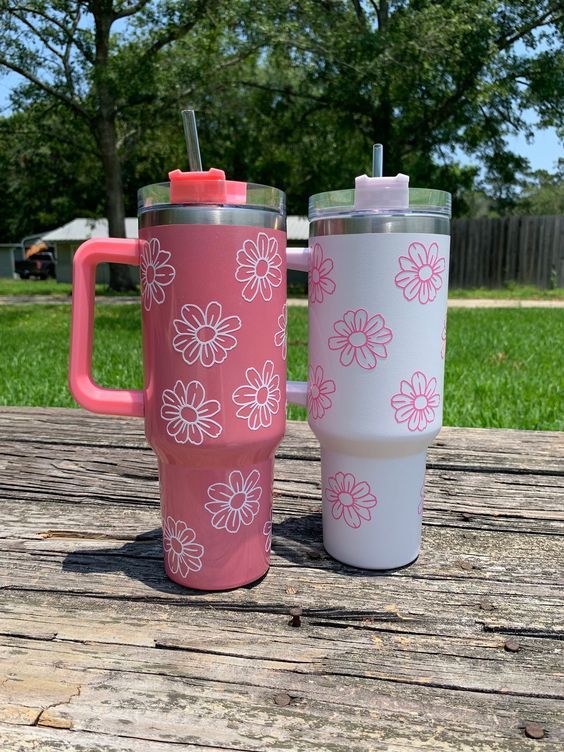 two pink and white tumblers sitting on top of a wooden table next to each other