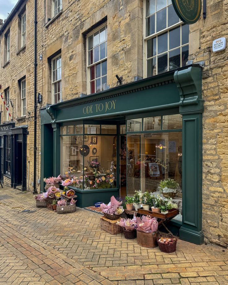 an old brick building with flower shops on the street