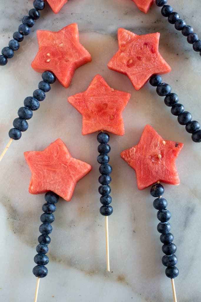 watermelon and blueberries on toothpicks are arranged in the shape of a christmas tree