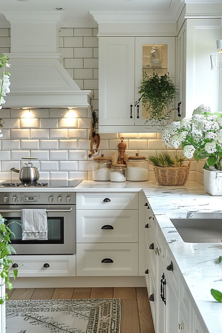 a kitchen with white cabinets and an oven in the center is lit by lights above the stove