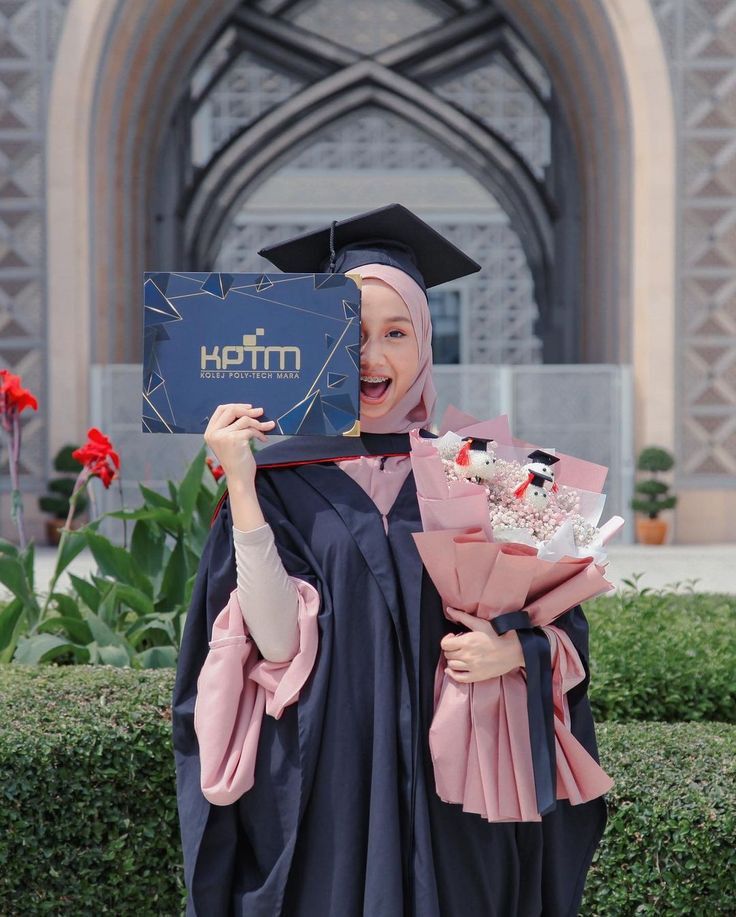 a woman in a graduation gown holding up a sign that says herm on it