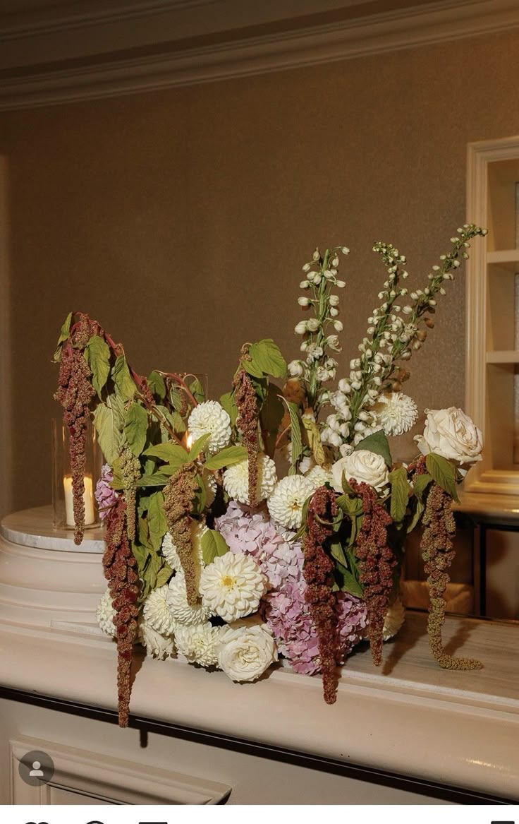 there is a vase with flowers on the mantle