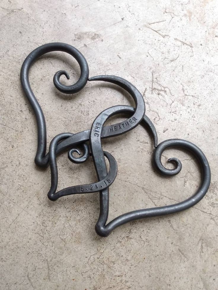 two metal heart shaped hooks sitting on top of a cement floor