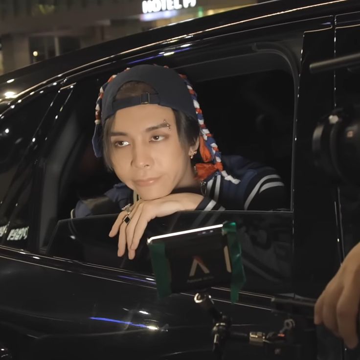 a man sitting in the driver's seat of a car with his hand on the door handle