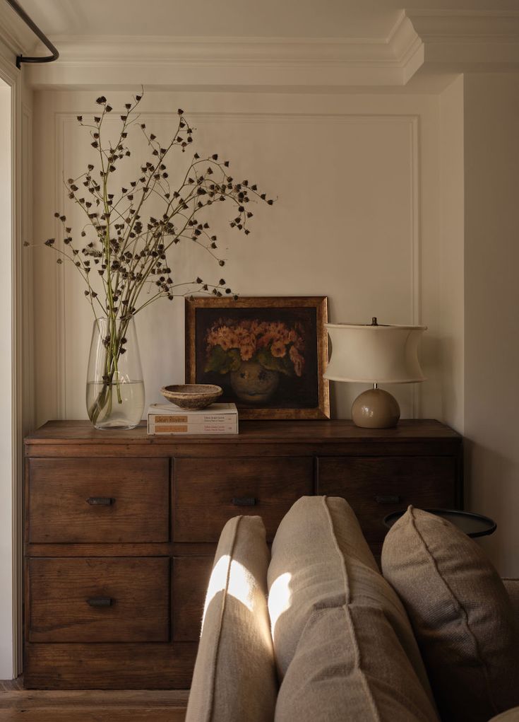 a living room with couches and a painting on the wall next to a dresser