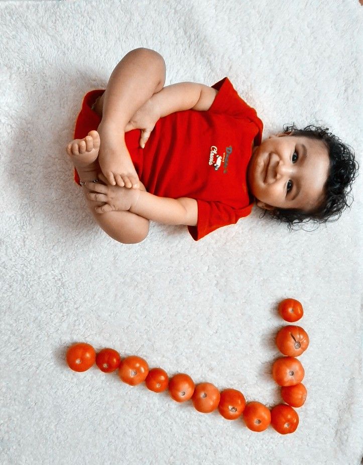 a baby is laying on the floor next to some tomatoes that spell out i love you