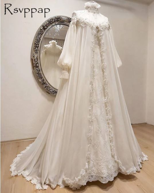 a white wedding gown on display in front of a round mirror with an ornate frame