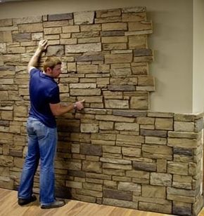 a man is working on a wall made out of stacked stone blocks in an office