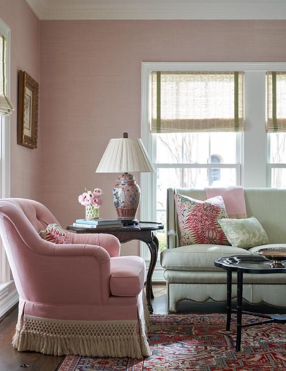 a living room with pink walls and furniture in front of a large window on the far wall