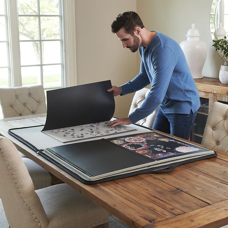 a man standing over a table with an open book on it and looking at the pages