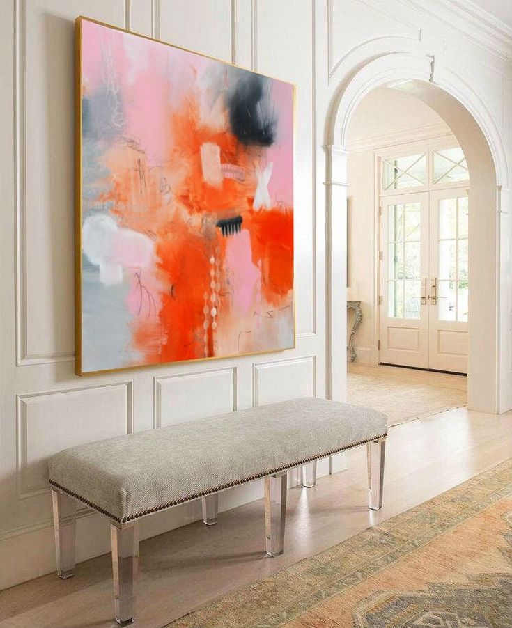 a large painting hanging on the wall above a bench in a room with white walls