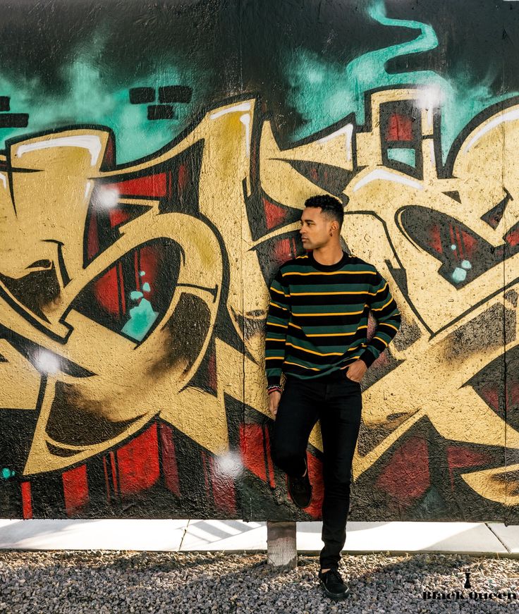 a man standing in front of a graffiti covered wall