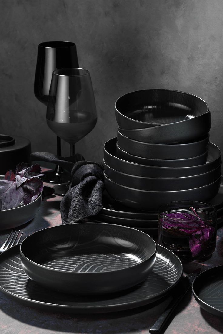 a table topped with lots of black plates and bowls