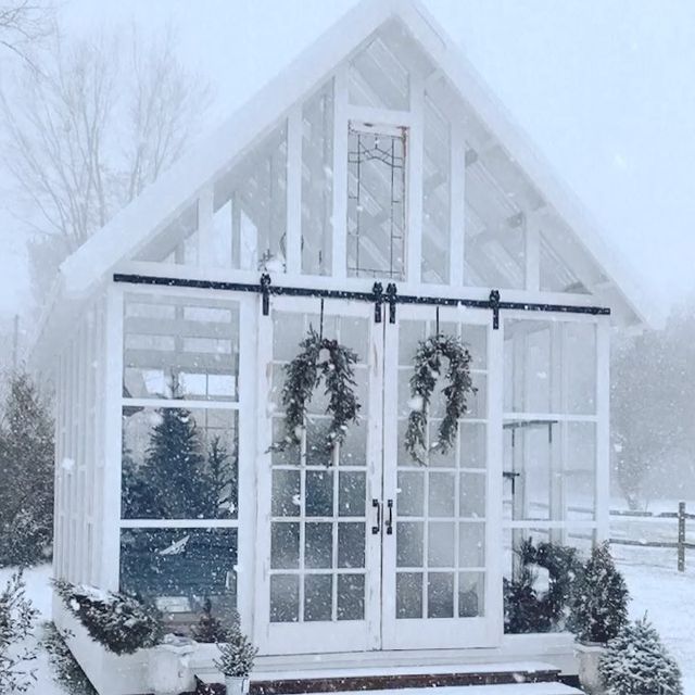 a small white house covered in snow with wreaths