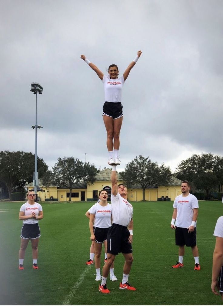 a woman standing on top of a soccer ball while holding her hands up in the air