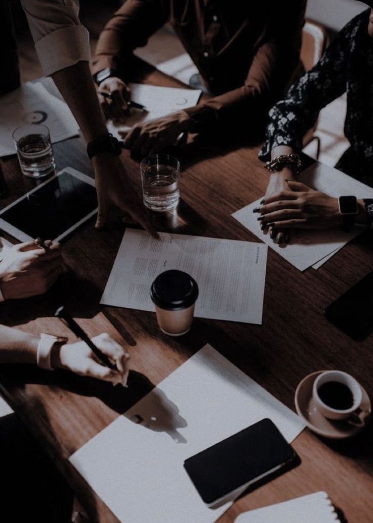 people sitting at a table with papers and pens