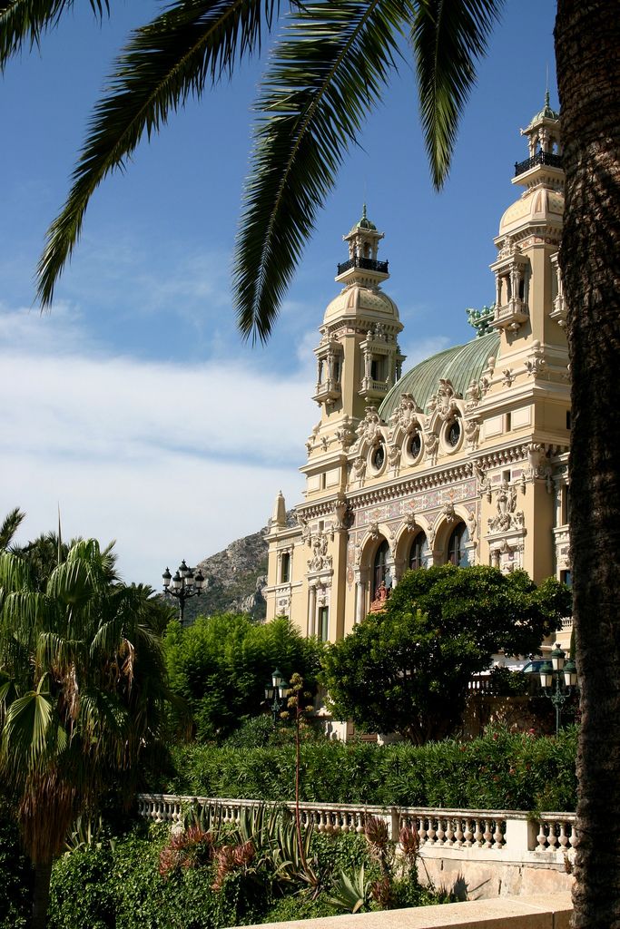 a large building with two towers on top of it's sides surrounded by greenery and palm trees