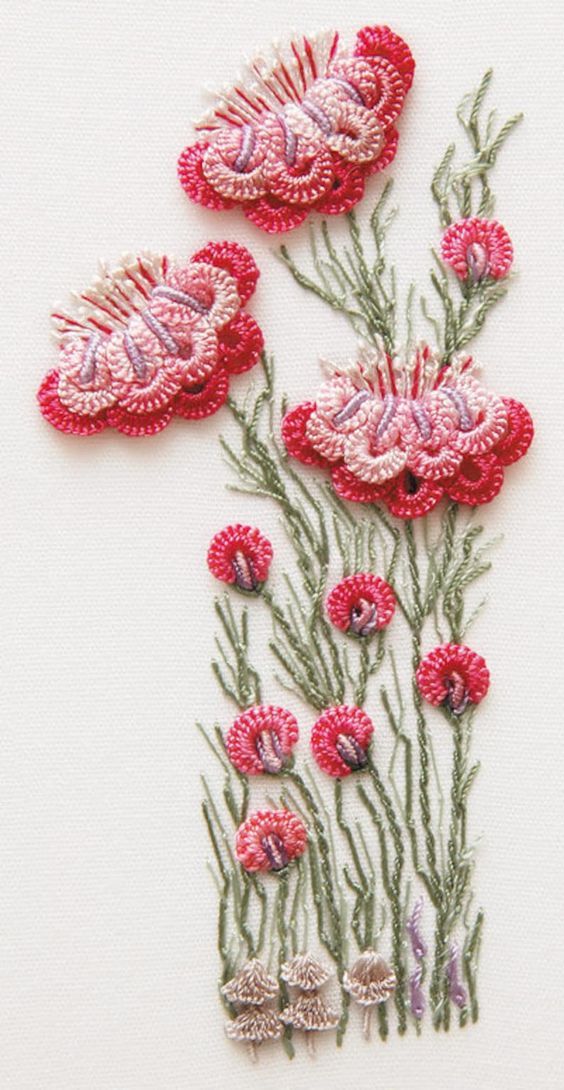 three red flowers with green stems on a white tablecloth, one is embroidered and the other has sequins