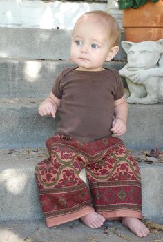 a baby sitting on the steps with his legs crossed