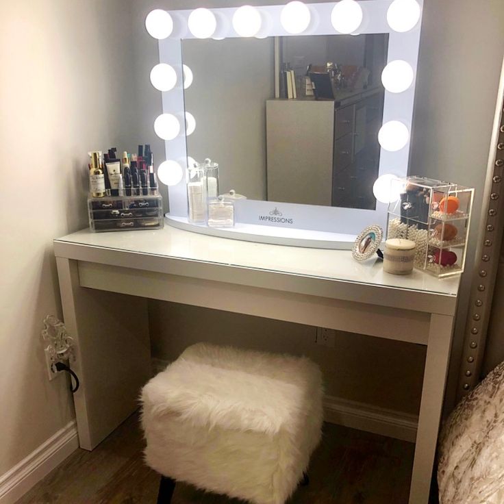 a white vanity with lights on it and a stool