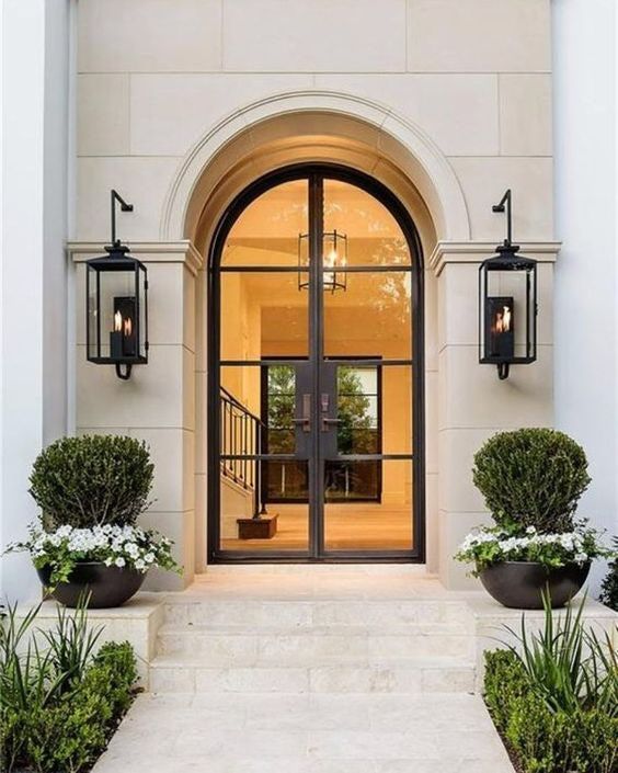 an entrance to a house with two large doors and some planters on the side