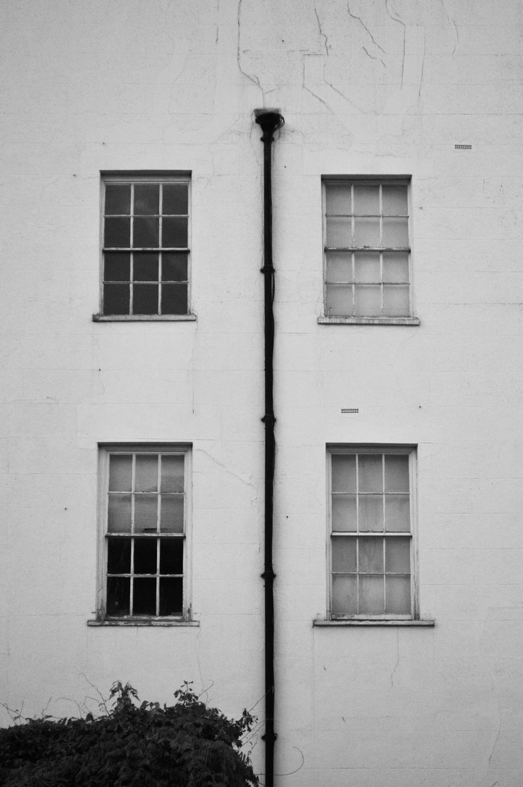 a black and white photo of two windows on the side of a building with a street light