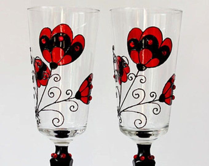 two wine glasses with red and black designs on them